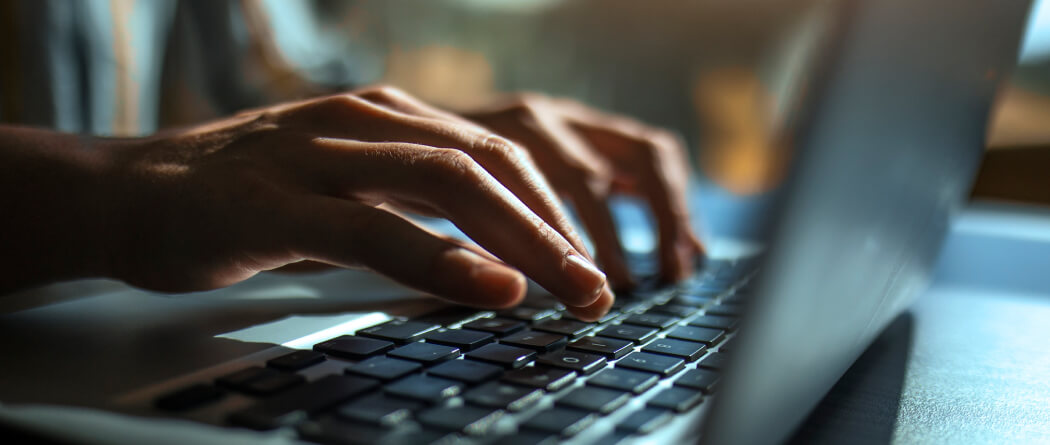 Close-up of hands typing on a laptop